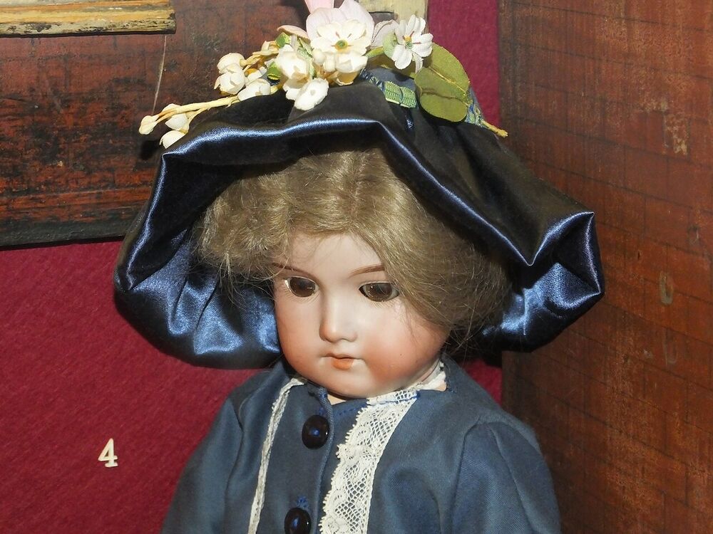 Armand Marseille bisque-headed doll with glass eyes, mohair wig, blue satin hat with flowers and a buttoned blue jacket