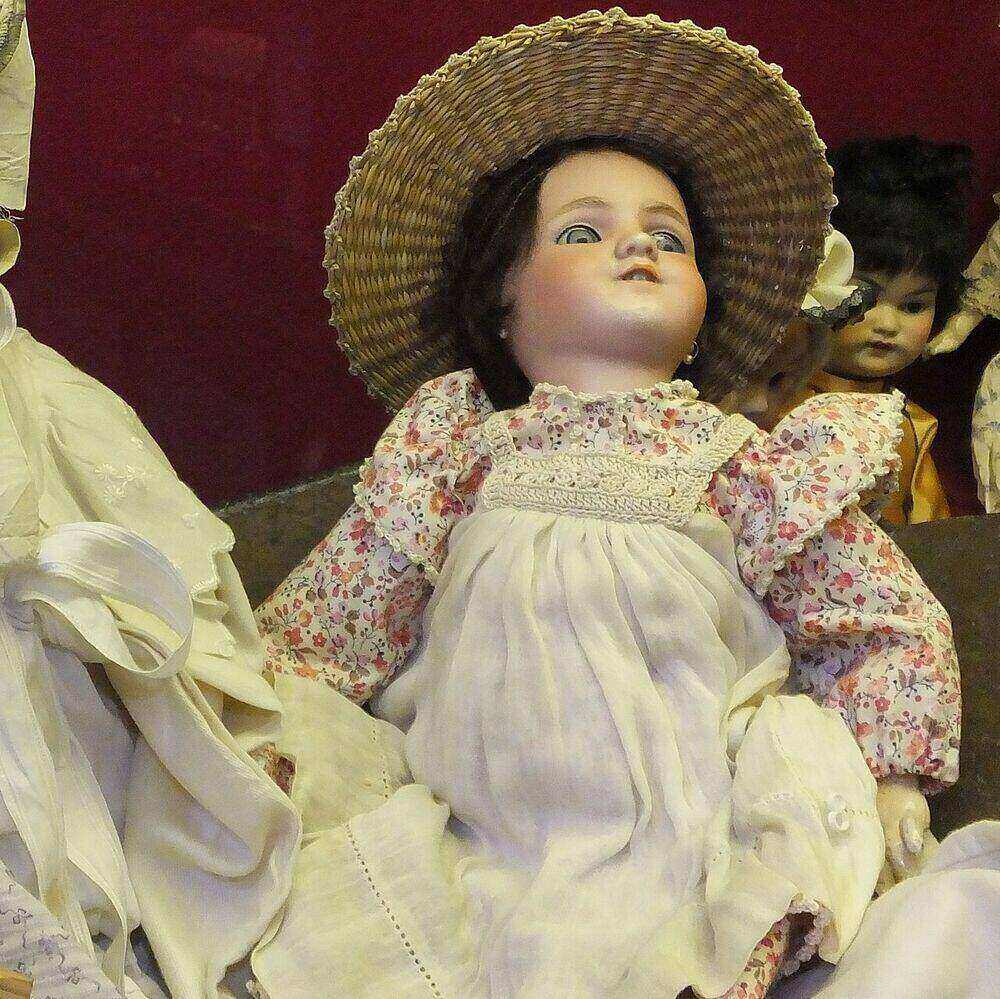 Simon & Halbig bisque doll with open mouth, glass eyes, straw hat and floral dress on a composition body