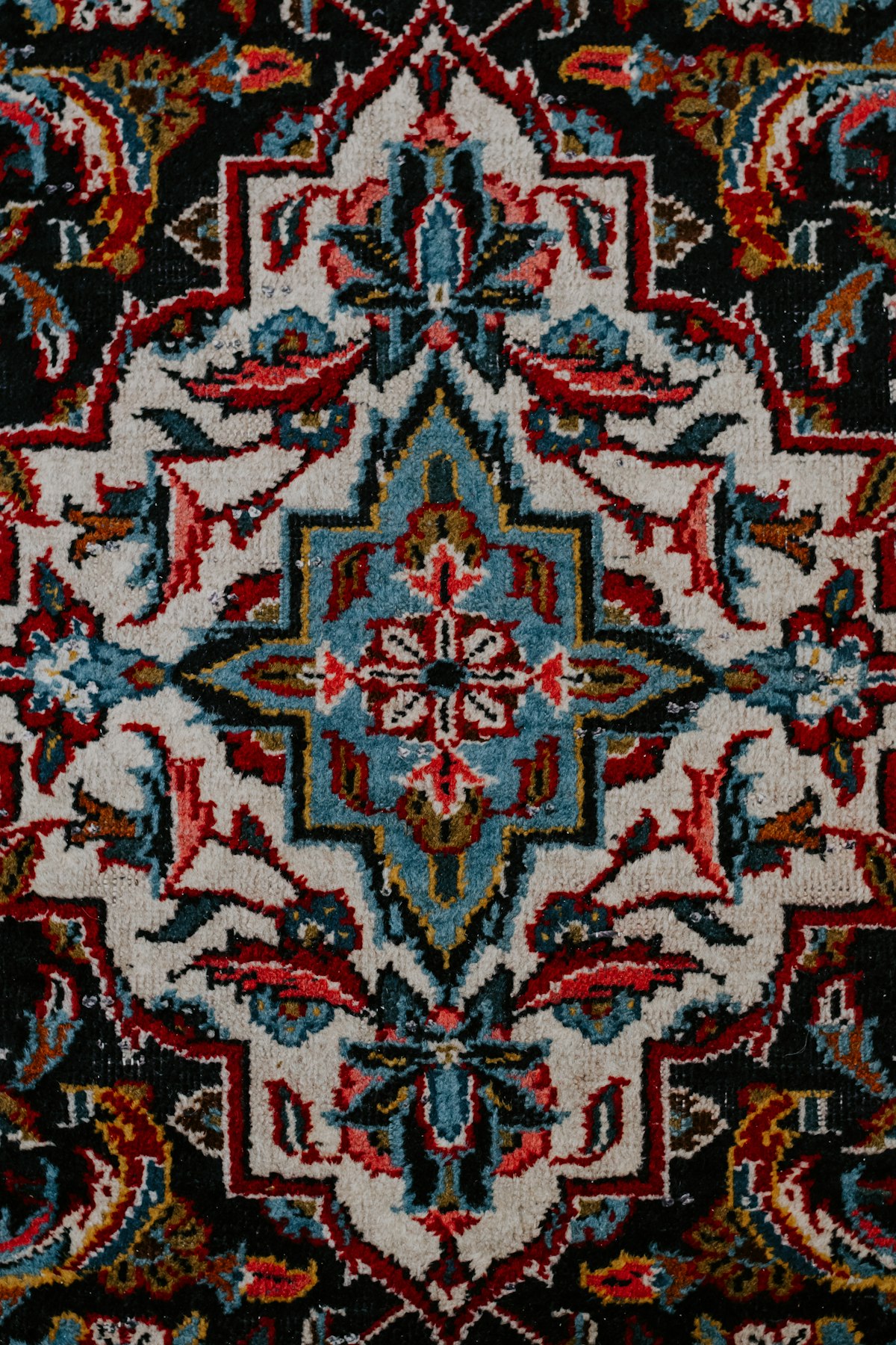 Close-up of a handmade oriental rug showing floral pile, colour variation and weave texture